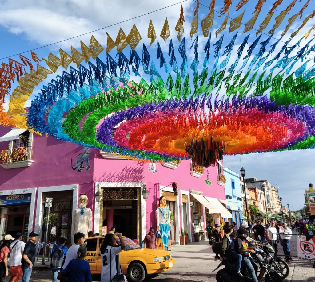 Rue colorée décorée de papel picado à Oaxaca, avec façades roses et taxi jaune